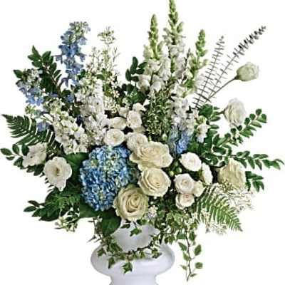 White and blue floral arrangement in a white pedestal vase