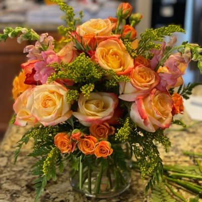 Bouquet of peach and orange roses in a clear glass vase