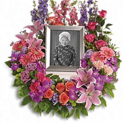 Floral memorial wreath around a framed portrait with pink and purple flowers