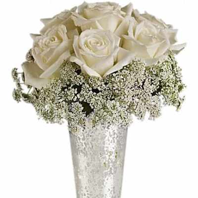 White roses in a tall silver vase with baby's breath