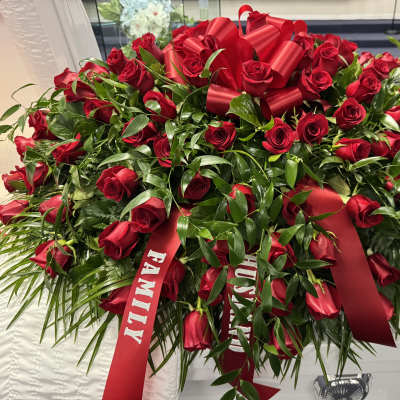 Large red rose arrangement with satin ribbons on a casket