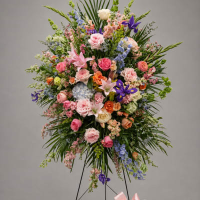 Large standing floral spray with pink, purple, and white blooms on a black easel