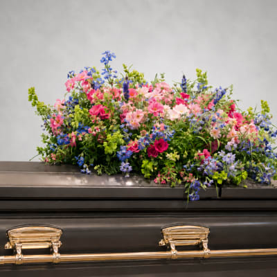 Colorful floral spray arranged on top of a casket