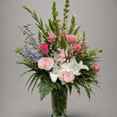 Tall mixed bouquet in a clear glass vase with pink, white, and blue flowers
