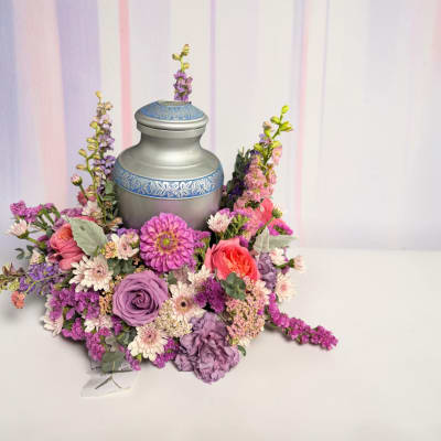 Floral arrangement around a silver urn with pink, purple, and white blooms