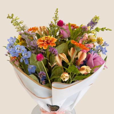 Mixed bouquet of colorful flowers wrapped in white paper