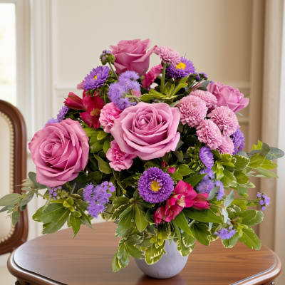 Pink roses and purple flowers arranged in a white vase