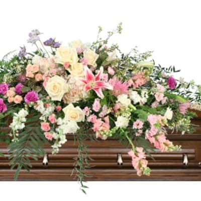Large pastel floral spray on a wooden casket