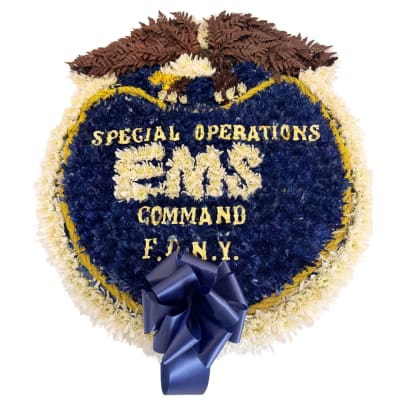 Heart-shaped floral tribute with blue, white, and gold lettering and a blue ribbon
