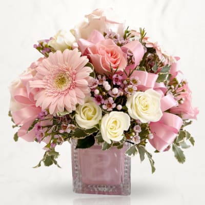 Pink and white flower arrangement in a glass vase with ribbon