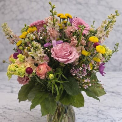 Mixed pink and yellow flower bouquet in a clear glass vase