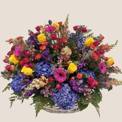Colorful mixed flower arrangement in a white basket