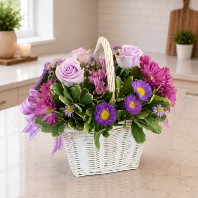 Lavender roses and purple daisies in a white basket with a ribbon