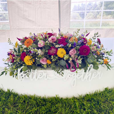 Large colorful wedding flower arrangement in a white container