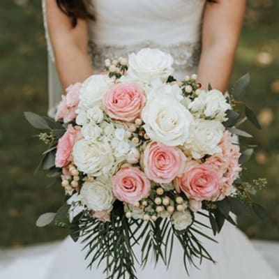 Bride holding a bouquet of white and blush pink roses