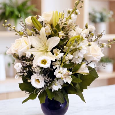White lilies and roses arranged in a dark vase