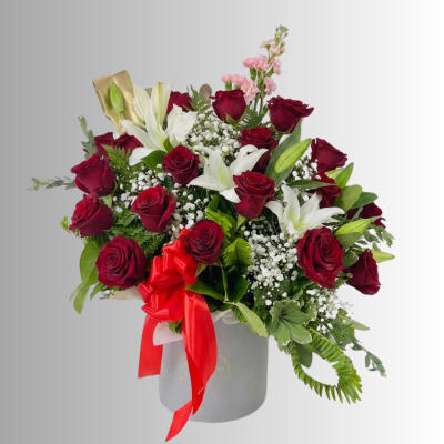 Bouquet of red roses and white lilies in a gray hat box with a red ribbon