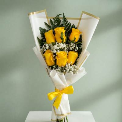 Bouquet of yellow roses wrapped in white paper with a yellow ribbon