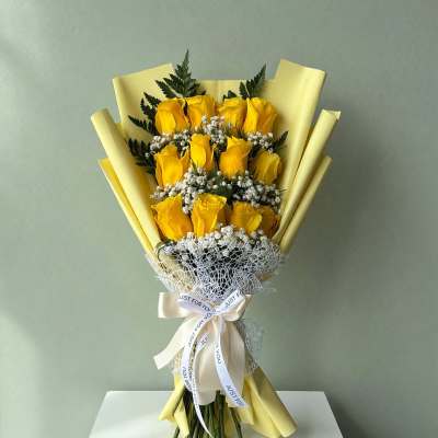 Yellow rose bouquet wrapped in pale yellow paper with a ribbon