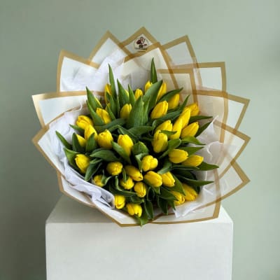 Bouquet of yellow tulips wrapped in white and gold paper