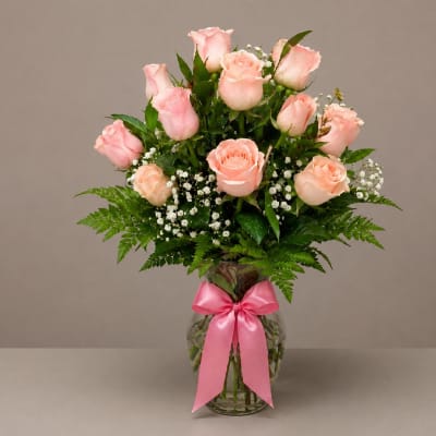 Pink roses in a glass vase with a pink ribbon