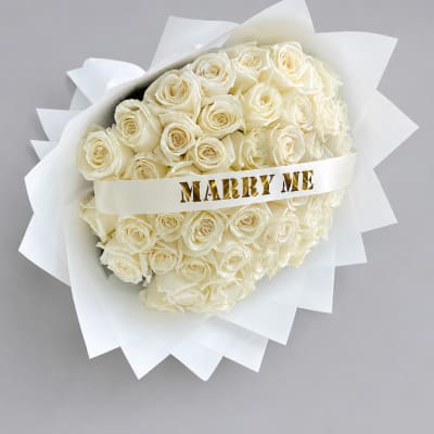 Bouquet of white roses wrapped with a "MARRY ME" ribbon