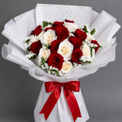 Bouquet of red and white roses wrapped in white paper with a red ribbon
