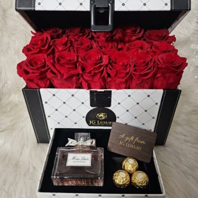 Open gift box filled with red roses and a perfume set with chocolates