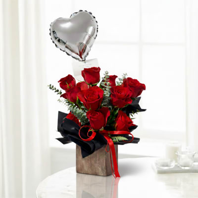 Red roses in a wooden box with a silver heart balloon