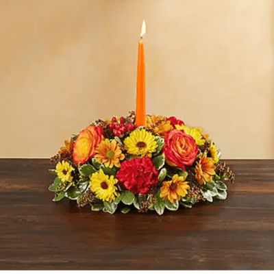 Low floral centerpiece with an orange candle in the middle