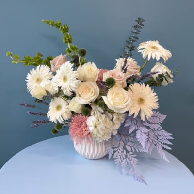 Mixed bouquet of white and blush flowers in a white vase