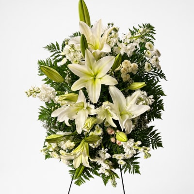 White lily and rose standing spray with greenery on a white background