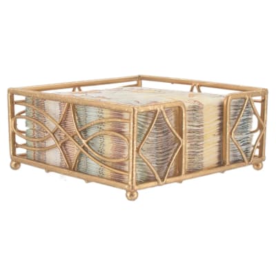 Decorative gold metal napkin holder with a stack of patterned napkins