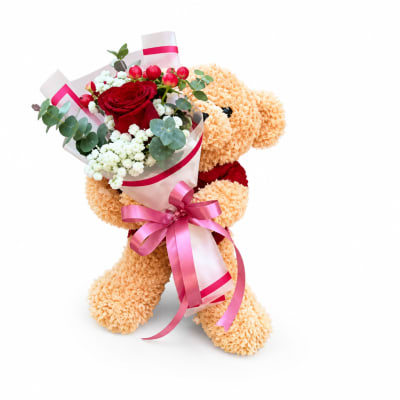 Teddy bear holding a bouquet of red roses and white flowers