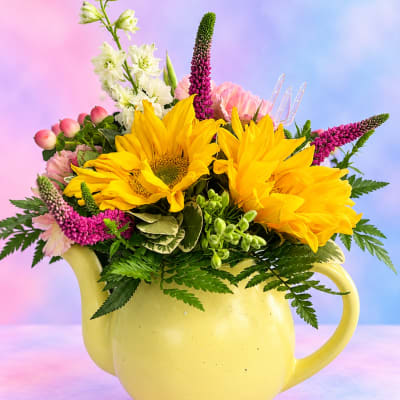 Yellow sunflowers and pink flowers arranged in a yellow pitcher
