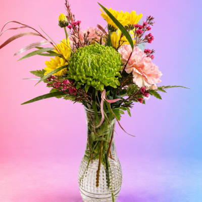 Mixed bouquet in a clear glass vase with green, yellow, and pink blooms