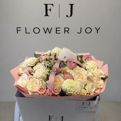 Bouquet of cream and blush roses with pale dahlias in a gift box