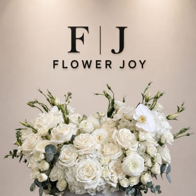 White rose arrangement in a gray vase with eucalyptus accents