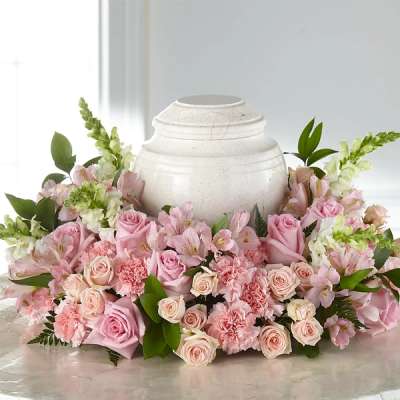 Pink roses and carnations arranged around a white urn