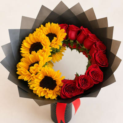 Bouquet of red roses and yellow sunflowers in black wrap with a red ribbon