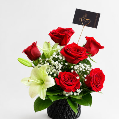 Red roses and white lilies arranged in a black vase