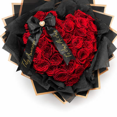 Heart-shaped bouquet of red roses wrapped in black paper with a ribbon