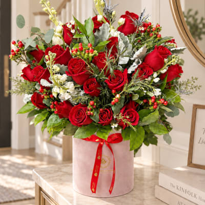 Large bouquet of red roses in a pink hatbox with a red ribbon