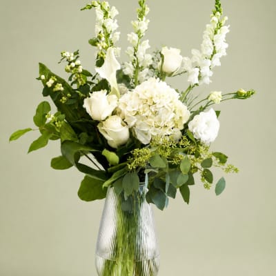White flowers arranged in a clear ribbed glass vase