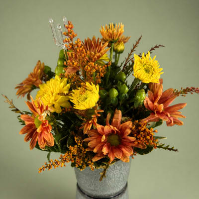 Orange and yellow chrysanthemum arrangement in a textured silver pot