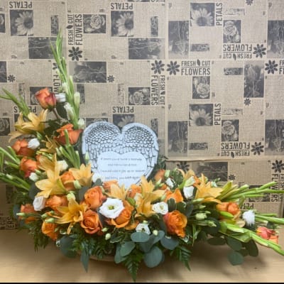 Orange and white floral arrangement with a heart memorial plaque