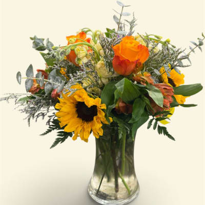 Bouquet of sunflowers and orange roses in a clear glass vase
