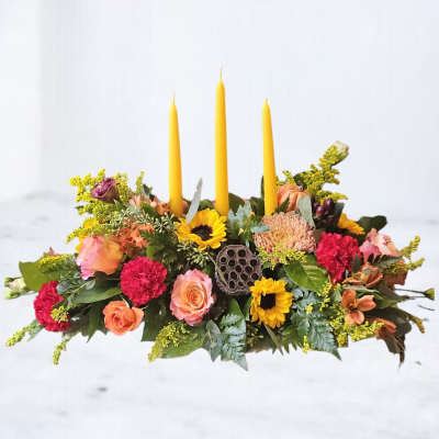 Low floral centerpiece with yellow taper candles and mixed blooms