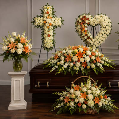 Funeral casket surrounded by white and orange floral sprays and baskets