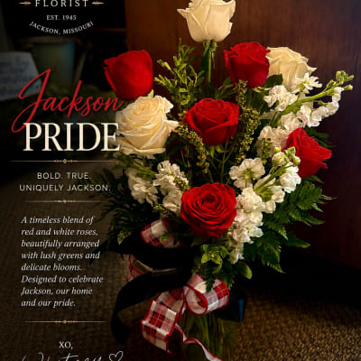 Red and white roses arranged in a glass vase with a plaid ribbon